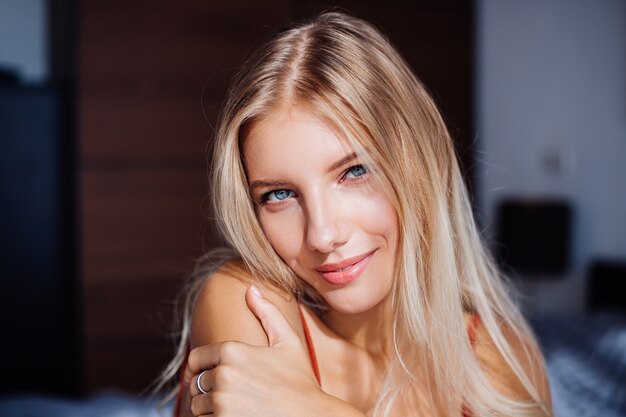 Attractive cute caucasian european woman enjoys beautiful sunrise light by window, she is on bed at home