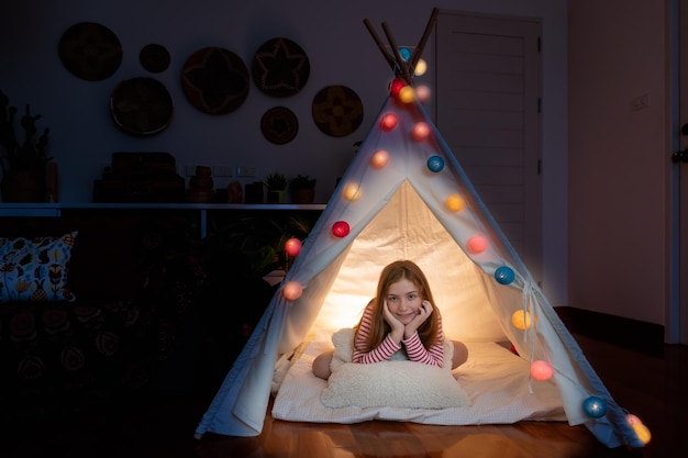 Free photo attractive cute girl sitting inside tepee tent in her bedroom enjoy happy time