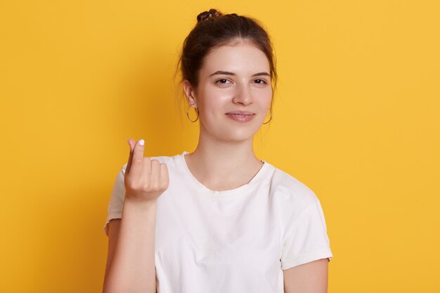 Attractive dark haired young woman shoving money gesture with her fingers