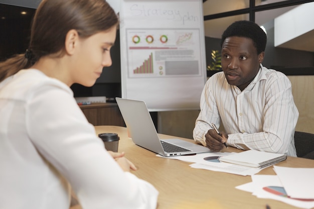 Attractive dark skinned male recruiter interviewing nervous young Caucasian female