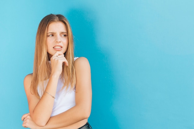 Free photo an attractive disgusted young woman standing against blue background