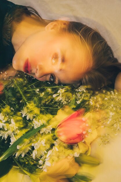 Привлекательная мечтательная женщина лежит с букетом цветов