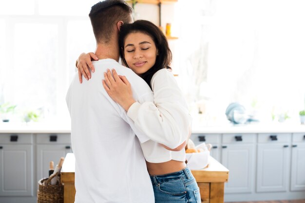 Attractive ethnic young woman hugging boyfriend with closed eyes