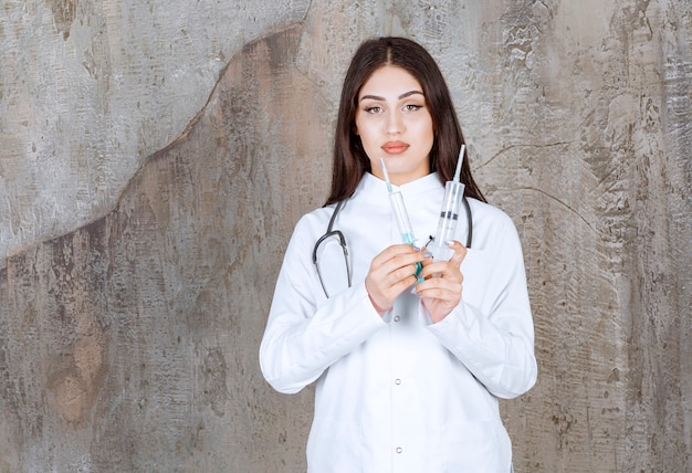 An attractive family doctor holding syringes and looking at front