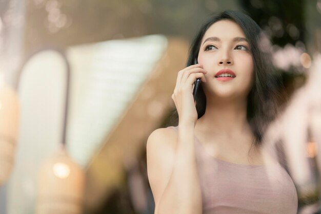 매력적인 여성 성인 여성 캐주얼 천 행복 대화 긍정적인 표정 손 잡고 스마트폰 통신 야외 상점의 전망을 반영