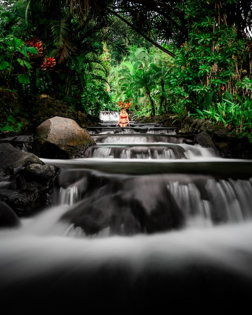 Free photo attractive female in a bikini sitting in a beautiful river surrounded with greenery