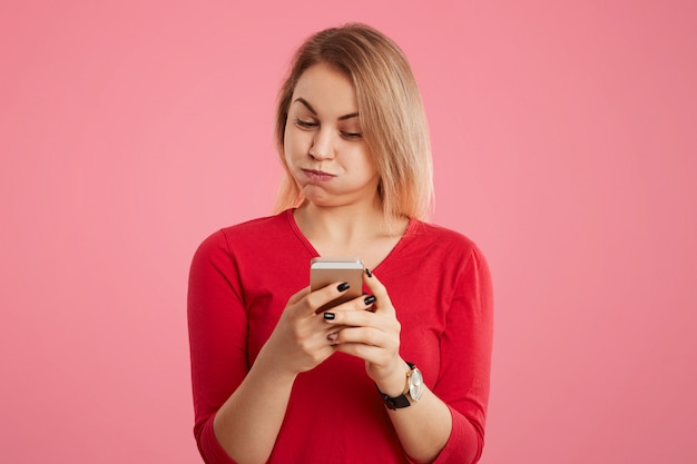 Free photo attractive female blows cheeks as being tired of messaging on smart phone