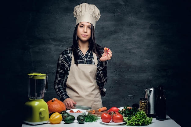 Attractive female chef preparing vegetable juice in a blender