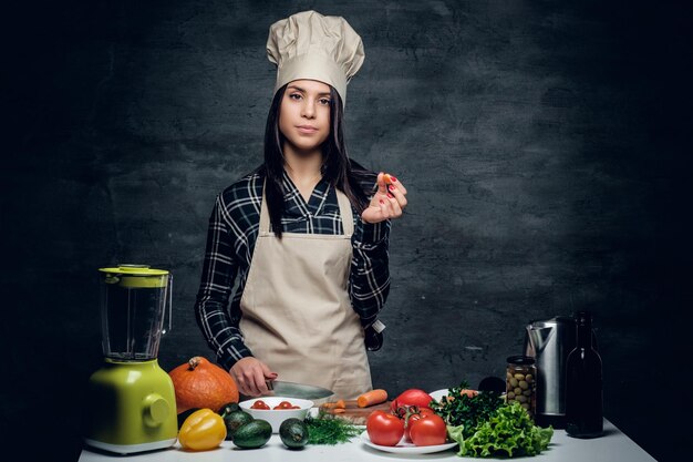 ブレンダーで野菜ジュースを準備する魅力的な女性シェフ。