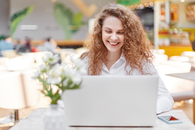 Attractive female freelancer works remotely on portable laptop computer