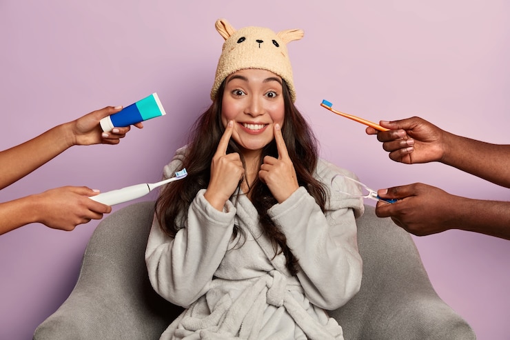 Free Photo attractive female model brushes teeth regularly, wears funny domestic hat and bathrobe