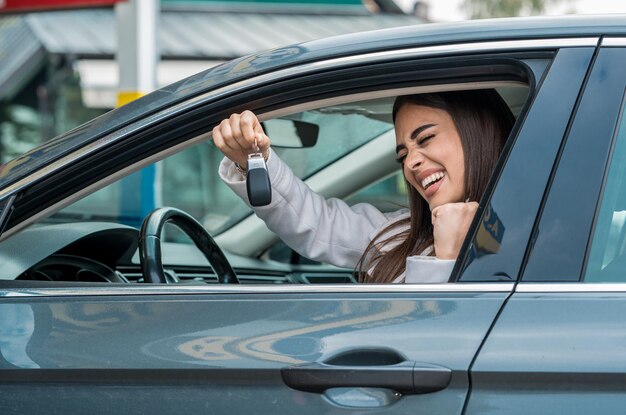 彼女の車のハンドルの後ろでポーズをとる魅力的な女性