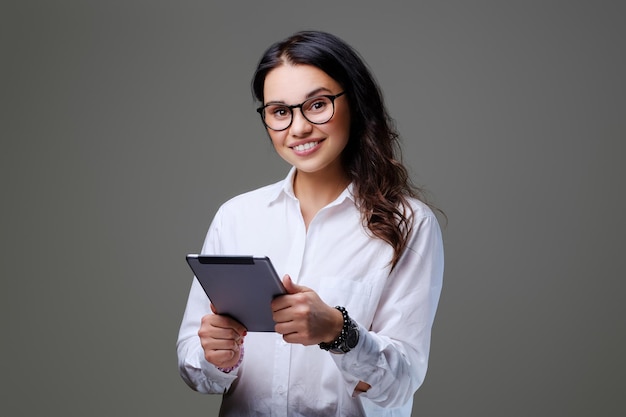 The attractive female student holds tablet PC. Isolated on grey background.