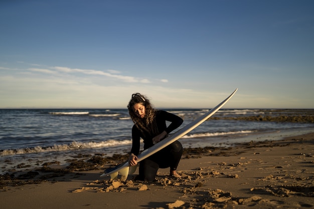 attractive female waxing her surfboard at the beach in Spain