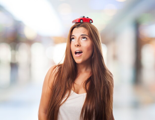 Attractive female with a car model on her head