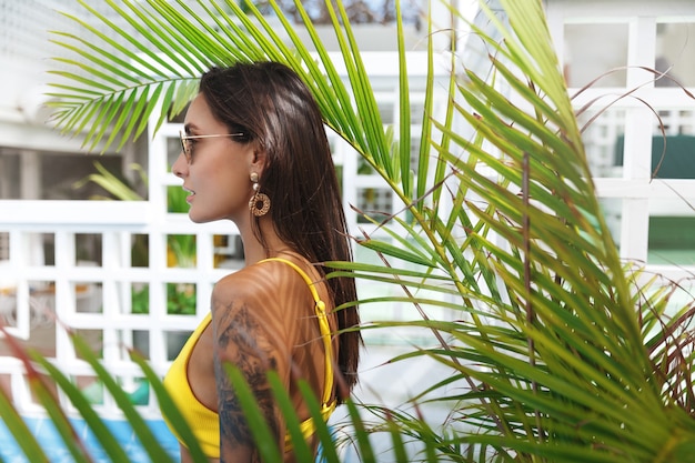 Foto gratuita donna attraente con una splendida abbronzatura posa vicino alla piscina al popolare.