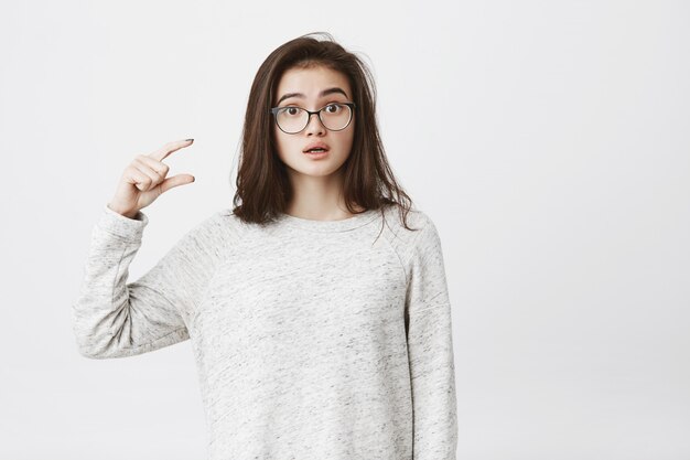 Attractive female woman showing something small and tiny with gesture