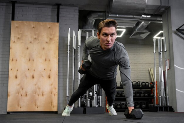 Attractive fit man working out indoors with dumbbells