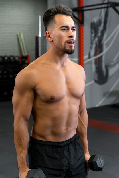 Attractive fit man working out indoors with dumbbells