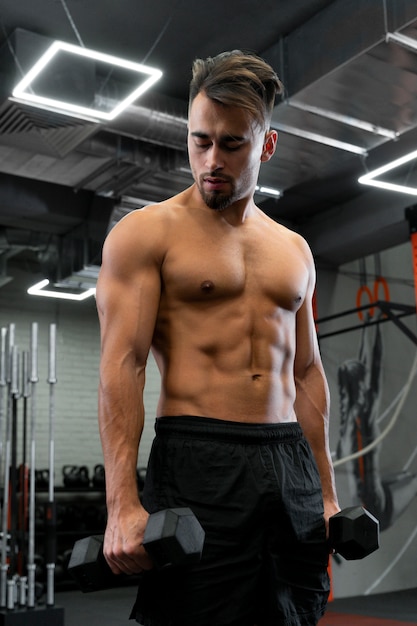 Attractive fit man working out indoors with dumbbells