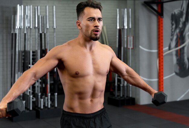 Attractive fit man working out indoors with dumbbells