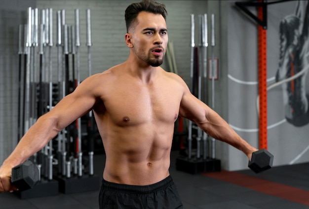 Attractive fit man working out indoors with dumbbells