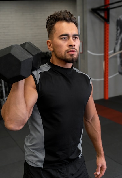 Attractive fit man working out indoors with dumbbells