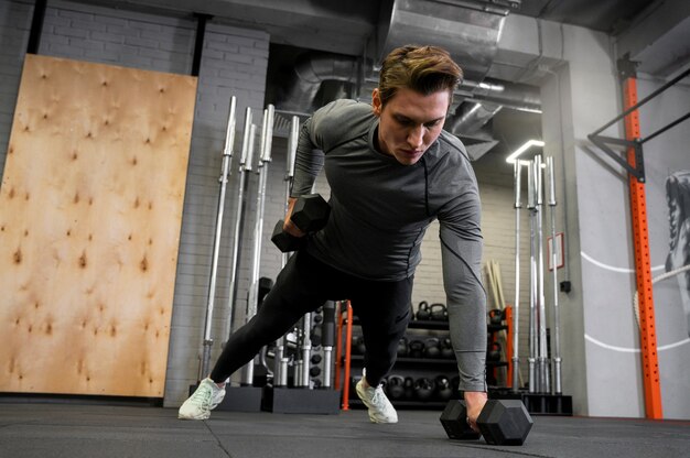 Attractive fit man working out indoors with dumbbells