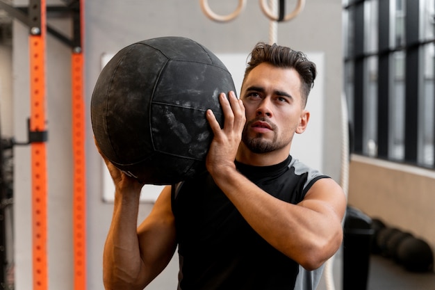 Привлекательный мужчина, тренирующийся в помещении с мячом для упражнений