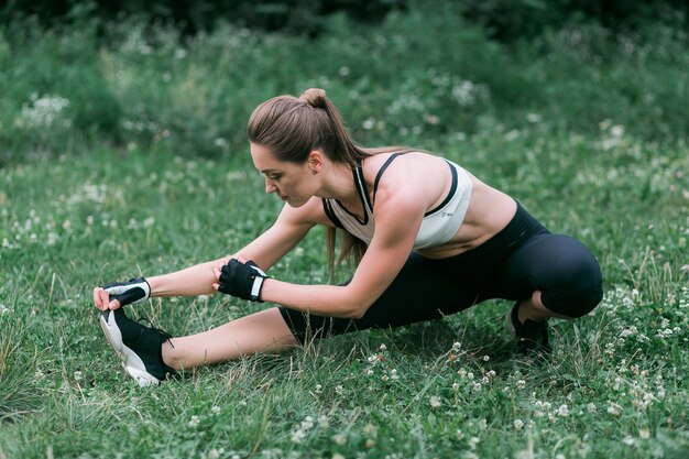 Attractive fit young woman does warming up before a work out on the backyard