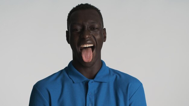 Attractive funny African American guy showing tongue on camera and laughing over white background Joyful expression