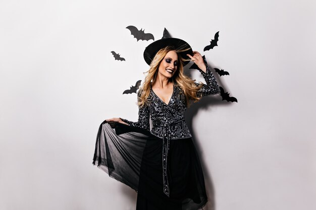 Attractive girl in carnival attire smiling . Refined blonde witch celebrating halloween.