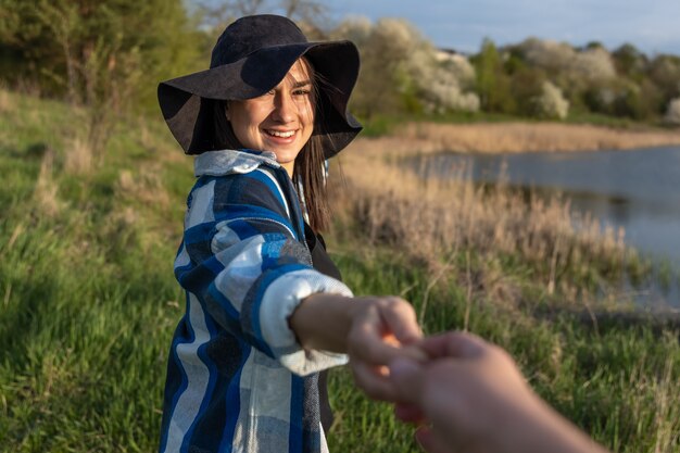 Attractive girl in a hat at sunset on a walk by the lake