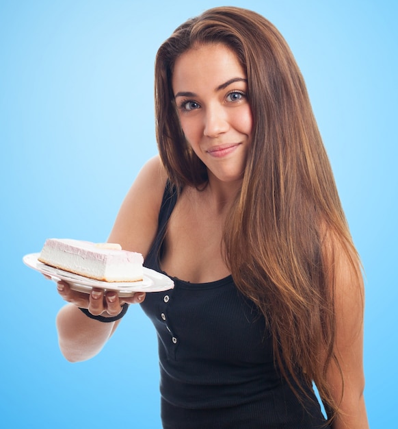 Привлекательная девушка держит сливочный кусок пирога.