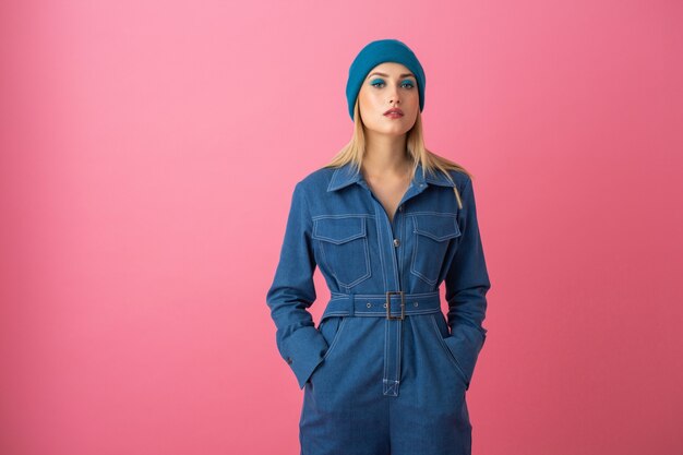 Attractive girl posing on pink background in denim overall fashion trend