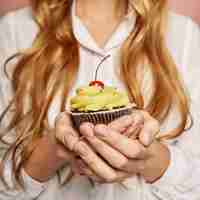 Free photo attractive girl in a white shirt is holding cupcakes