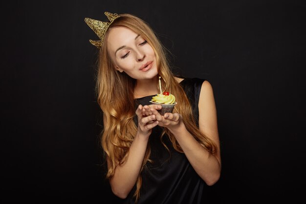 Attractive girl with a crown and cupcake