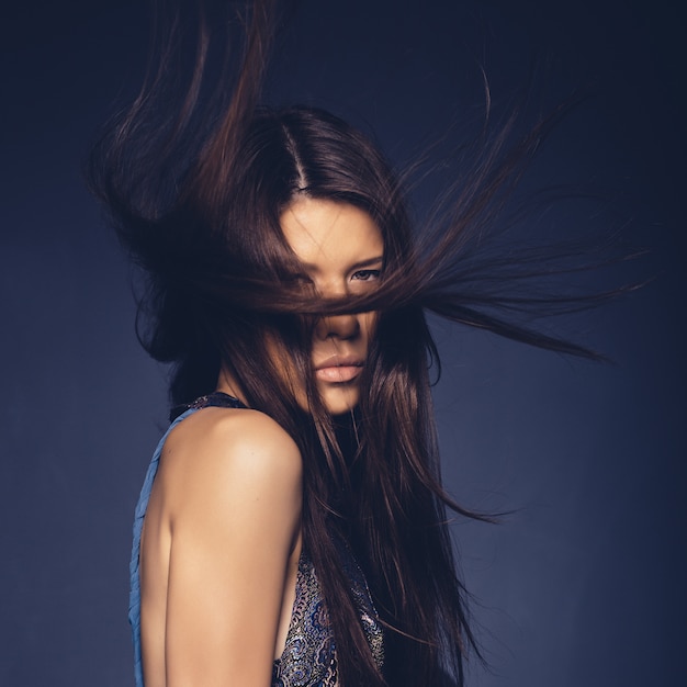Foto gratuita ragazza attraente con i capelli di volo che posano nello studio