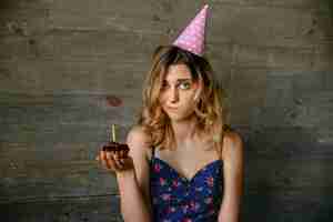 Free photo attractive girl with frustrated face after blowing out the candle on the cupcake