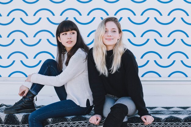 Attractive girls sitting together on street