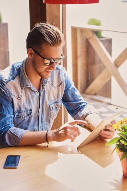 Attractive guy using a tablet PC in a cafe near the window.