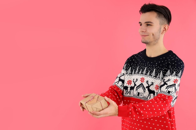 Attractive guy with christmas gift on pink background