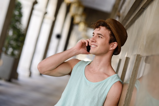帽子は電話で話しを持つ魅力的な男