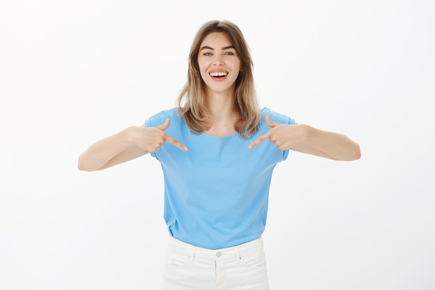 Attractive happy blond woman pointing at your logo, showing company banner