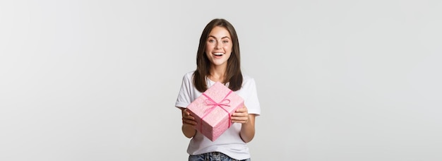 Free photo attractive happy brunette girl holding birthday gift and smiling cheerful