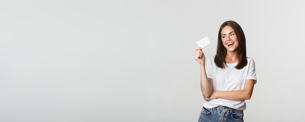 Free photo attractive happy brunette girl laughing and holding credit card white background