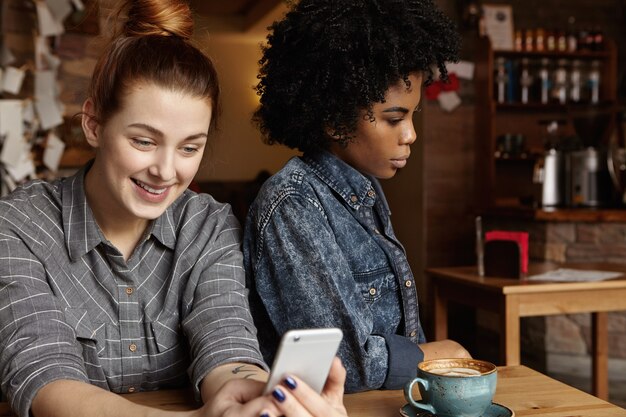 attractive happy caucasian woman with hair bun messaging online via social networks