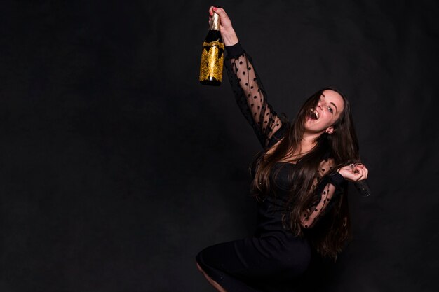 Attractive happy lady in evening dress with bottle of drink