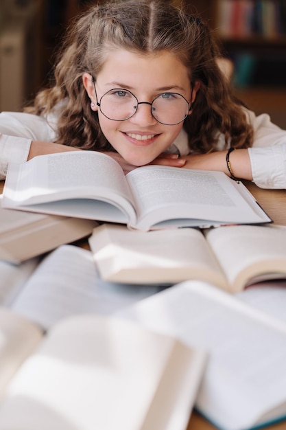 机に座って、大学図書館で勉強している魅力的な幸せな若い女の子の学生