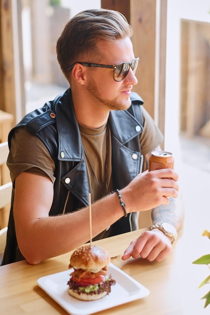 Free photo attractive hipster dressed in leather jacket eating a vegan burger.